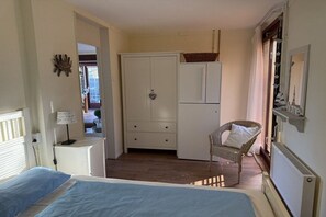 Ein Schlafzimmer mit Bett, Schrank, Stuhl und Heizkörper.