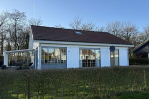 Ein modernes Haus mit einem großen Glasfenster, einer überdachten Terrasse und der Hausnummer 91 an der Wand.