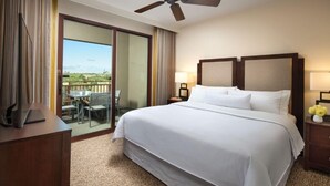 Quarto de hotel com uma cama grande, uma escrivaninha, uma cadeira, um abajur e vista para o exterior.