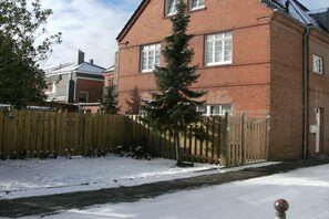 Ein zweigeschossiges Backsteinhhaus mit Holzzaun und verschneitem Grund.