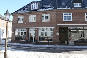A brick building with large windows and a shop on the ground floor. - Holiday apartment with 1 bedroom (Borkum)