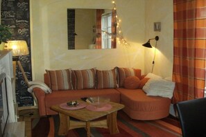 Ein gemütliches Wohnzimmer mit einer Couch, einem kleinen Tisch, einer Lampe und einem Spiegel.