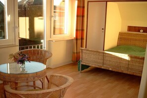 A room with a bed, a round table with chairs, and a window with curtains. - Villa Renate on the North Sea (Cuxhaven)