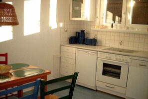 Een keuken met witte kastjes, een fornuis, een vaatwasser en een raam.