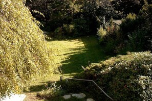 A pathway leading through a garden with a grassy area and dense foliage on either side. - Villa Renate on the North Sea (Cuxhaven)