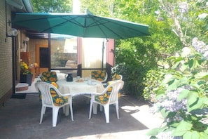 An outdoor patio with a table and chairs, a green umbrella, and a brick wall. - "To the Sunflower"||Borkum (Borkum)