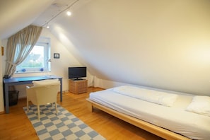 A bedroom with a bed, a desk, a chair, a television, and a window with curtains. - Holiday apartment with 3 bedrooms (Borkum)