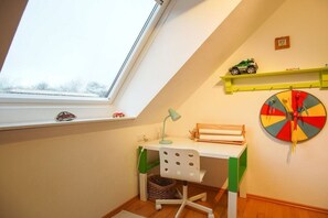 Une chambre d’enfant avec un bureau, une chaise et une fenêtre.
