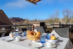 An outdoor dining area with a table set for breakfast, including bread, eggs, and fruit. - Holiday apartment with 3 bedrooms (Borkum)