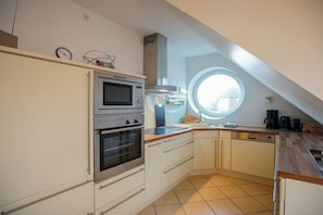A compact kitchen with a built-in oven, microwave, and a window above the sink. - Holiday apartment with 3 bedrooms (Borkum)