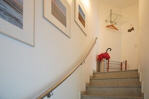 A staircase with a metal handrail, a red umbrella, and framed pictures on the walls. - Holiday apartment with 3 bedrooms (Borkum)