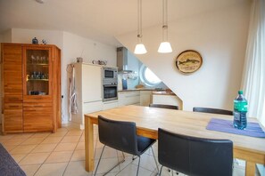A modern kitchen with a dining area, wooden cabinets, and a wall-mounted fish plate. - Holiday apartment with 3 bedrooms (Borkum)