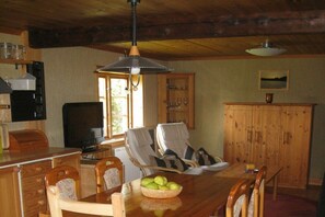 A dining area with a wooden table, chairs, a basket of fruit, and a television. - Holiday home with 2 bedrooms (Filipstad)
