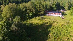 Ein rotes Gebäude mit einer weißen Veranda, umgeben von dichtem Wald.