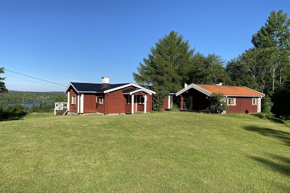 A two-story house with a red exterior and a grassy yard. - Holiday home with 2 bedrooms (Filipstad)