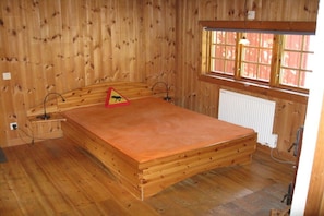 A wooden-paneled room with a bed, a radiator, and a window with a view. - Holiday home with 2 bedrooms (Filipstad)