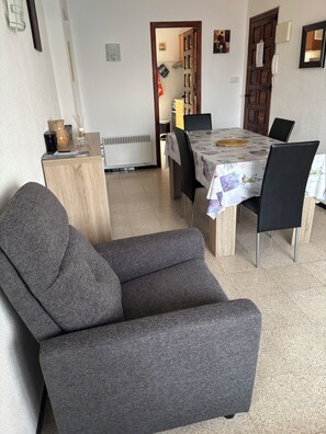 Un salon avec un canapé gris, une table basse en bois et une table à manger avec des chaises.