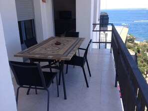 Un balcon avec une table et des chaises, donnant sur la mer.