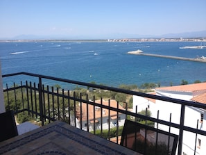 A balcony with a view of the sea, buildings, and a distant mountain range. - Two-bedroom apartment near the ocean (roses)