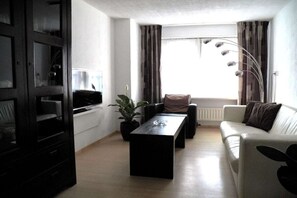 A living room with a sofa, a coffee table, a potted plant, and a window with curtains. - ||--------------------House at Domburg----------------|| (Domburg)