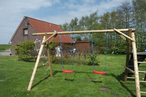 A wooden swing set with two swings in a grassy yard. - Holiday home with 1 bedroom (Bensersiel)