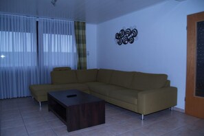 A living room with a sofa, a coffee table, and a decorative wall piece. - Holiday home with 1 bedroom (Bensersiel)