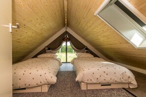 Ein Zimmer mit zwei Betten, einer geneigten Decke und einem Oberlicht.