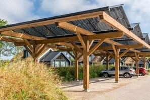 Ein überdachter Außenbereich mit Solaranlagen, Holzbalken und einem Kiesweg.