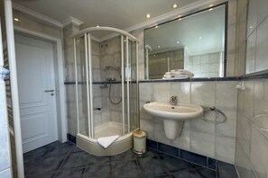 Un baño con ducha de vidrio, un lavamanos y un espejo.