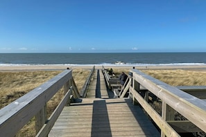 Un muelle de madera que conduce a una playa con vistas despejadas al océano.