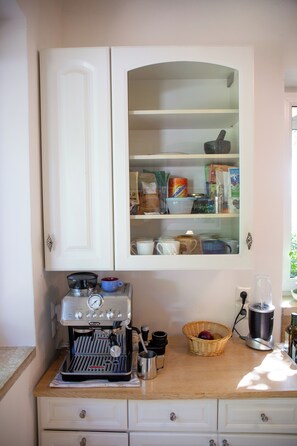 A kitchen area with a coffee machine, a cabinet with glass doors, and a countertop with various items.