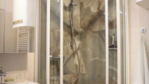 Un baño moderno con ducha de vidrio, tocador de madera y lavamanos blanco.