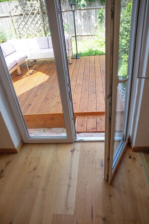 A wooden deck with a glass door leading to an outdoor area.