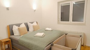 Un dormitorio con cama, mesitas de noche, una ventana y un radiador.