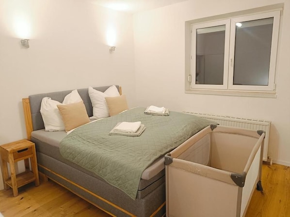 A bedroom with a bed, bedside tables, a window, and a radiator.