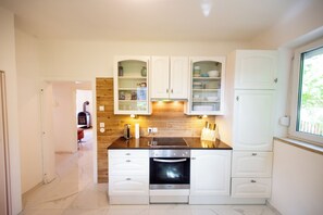 A modern kitchen with white cabinets, a built-in oven, and a microwave.