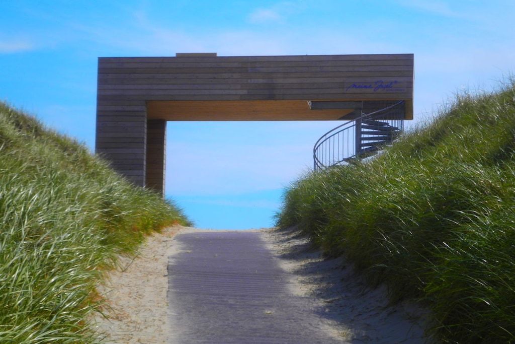 Ein Weg führt zu einer Holzhütte mit einer Wendeltreppe.