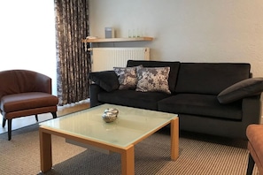 Ein Wohnzimmer mit Sofa, Sessel und Couchtisch.