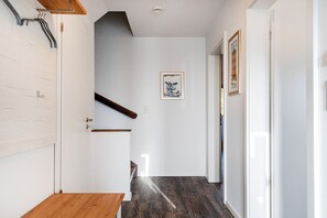 Ein Flur mit einer Holzbank, einer Treppe und einem gerahmten Bild an der Wand.