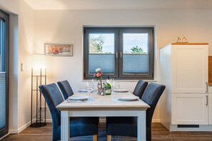Ein Essbereich mit einem Tisch für vier Personen, einer Stehlampe und einem Fenster mit Jalousien.
