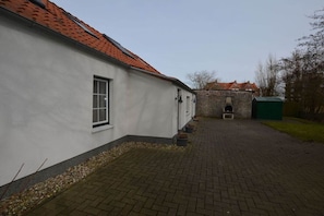 Ein Gebäude mit roten Ziegeldächern, einem gepflasterten Innenhof und einer Steinmauer im Hintergrund.