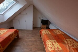 Ein Schlafsaalzimmer mit zwei Betten, einem Schrank, einem Fernseher und einem Oberlicht.