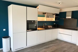 A modern kitchen with white cabinets, a black countertop, and a stainless steel range hood. - Holiday home with 4 bedrooms (Kamperland)