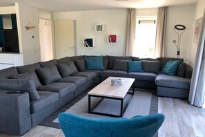 A modern living room with a sectional sofa, a coffee table, and a blue armchair. - Holiday home with 4 bedrooms (Kamperland)