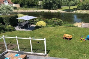 A backyard with a pond, a patio table, and a play area. - Holiday home with 4 bedrooms (Kamperland)