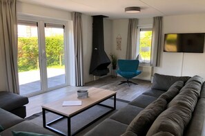 A modern living room with a sofa, a blue chair, a coffee table, and a fireplace. - Holiday home with 4 bedrooms (Kamperland)
