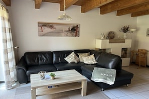 Ein Wohnzimmer mit einem schwarzen Ledersofa, einem Holztisch und einem Gemälde an der Wand.