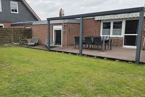 A covered patio area with a brick wall, a door, and a table with chairs. - Holiday apartment with 2 bedrooms (Berumbur)
