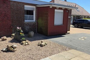 A small red building with a white garage door, number 10, next to a brick house. - Holiday apartment with 2 bedrooms (Berumbur)