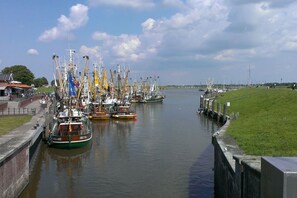 A canal with boats docked along the sides, a grassy area on the right, and a clear sky above. - Holiday apartment with 2 bedrooms (Berumbur)